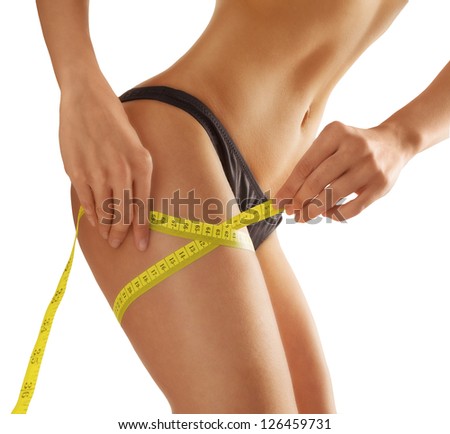 young woman measures her thigh. Isolated. Slim waist with a tape measure around it