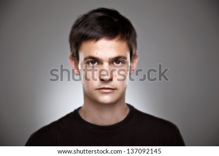 Attractive young man in studio looking at camera/ Portrait of a normal boy on a grey background