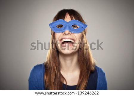 Beautiful young woman in studio looking up/ Portrait of a normal girl laughing with a blue mask