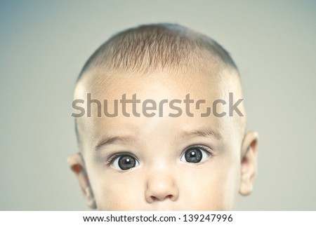 Baby portrait over grey background/ Adorable baby half face looking camera. Vintage style