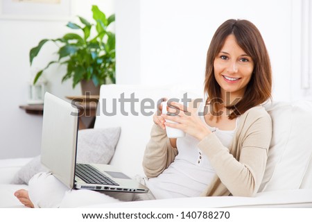 Woman take a coffee at home/Young woman lying on the couch and working with a laptop