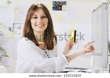 Young woman creative designer making payments online. / Young businesswoman with a credit card and pointing on the screen.