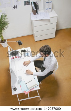 Young businessman typing a computer in office. Businessman with rimmed glasses working.