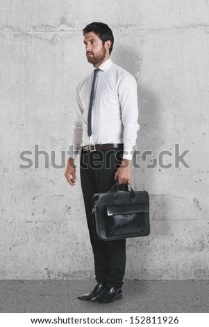 Young businessman standing with briefcase. Businessman on a grunge background.
