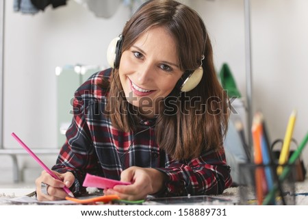 Young creative woman stretched in the floor listening music with headphones./ Casual blogger woman doing fashion sketches in her office.