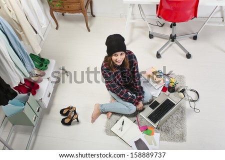 Young creative woman sitting in the floor with laptop./ Casual blogger woman working in her fashion office.