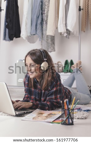Young creative woman stretched in the floor and listening music./ Casual blogger woman working with laptop in her fashion office.