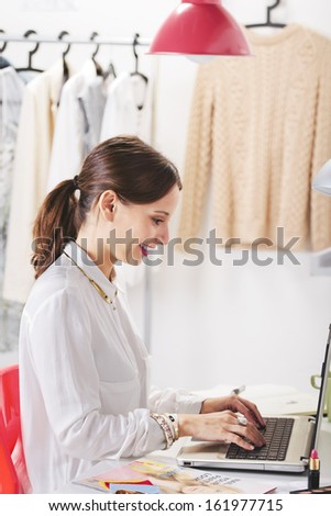 Young creative woman typing on a laptop in her office./ Fashion woman blogger working in a creative workspace.