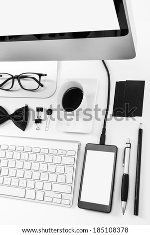 Overhead of essentials office objects in black and white./ Closeup of business objects in order on white desk.