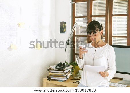 Beautiful businesswoman sending a message with cellphone. / Young entrepreneur woman working on home office.