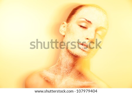 Luxurious mystical young woman with creative golden makeup gracefully posing