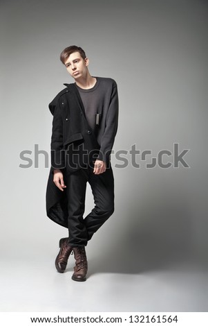 Fashion Shot of a young man in coat on grey background