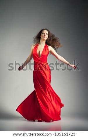 Gorgeous young ballet dancer wearing red dress over dark grey background