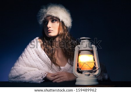 portrait of beautiful woman sitting with lantern over dark background