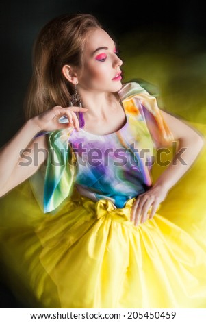 beautiful woman in long yellow dress posing dynamic in the studio