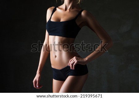 Slim tanned woman\'s body  over dark grey background