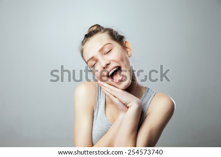 pretty young excited woman with her hands under chin, isolated against grey  background