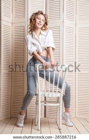 Young beautiful woman on chair in front of a jalousie