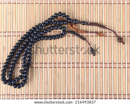 Tasbih on bamboo mat. Wooden rosary