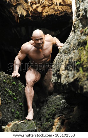 Muscular man climbs out of the cave