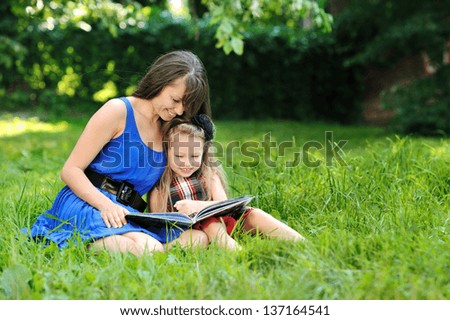 Mother and daughter reading book in a park