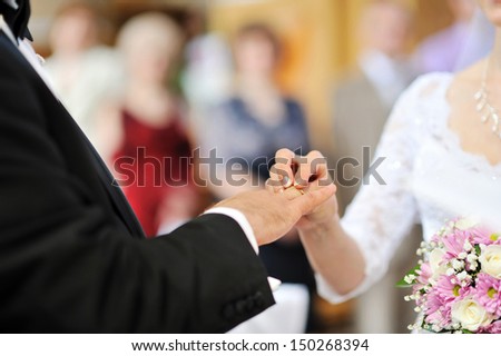 Bride putting a wedding ring on groom\'s finger