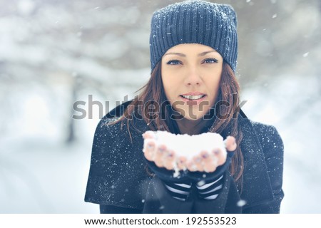 Young beautiful smiling girl holding snow in hands