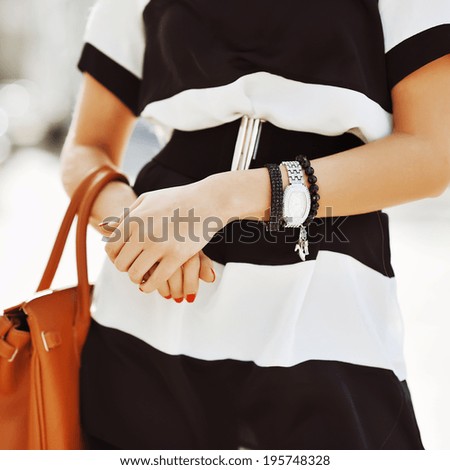Fashion shoot of a blonde woman wearing a jewelry, and holding bag in her hands