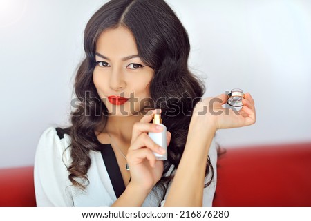 Woman with perfume, young beautiful girl holding bottle of perfume and smelling aroma