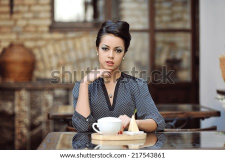Young beautiful woman having tea-party at restaurant