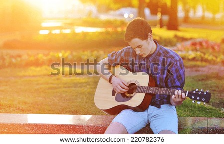 Practicing in playing guitar. Handsome young man playing on acoustic guitar