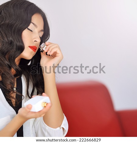 Woman with perfume. Beautiful girl holding bottle of perfume and smelling aroma