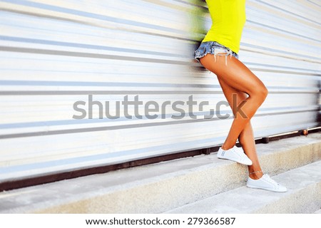 Sporty long sexy legs of a beautiful woman. Jeans shorts urban casual street style
