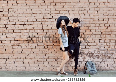 Young couple in love outdoor. Stunning sensual outdoor portrait of young stylish fashion couple posing near a wall
