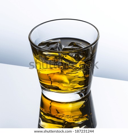 whiskey glass with ice cubes rocks alcohol and reflection drink and grey gradient background
