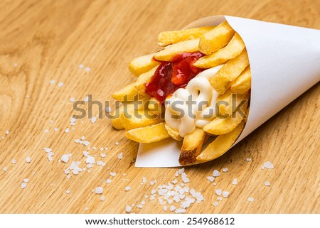 french fries in bag with salt on wooden background