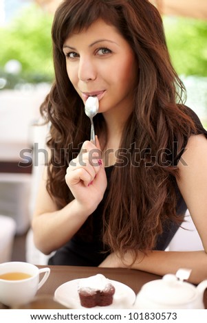 beautiful young woman sitting in a cafe eating cake