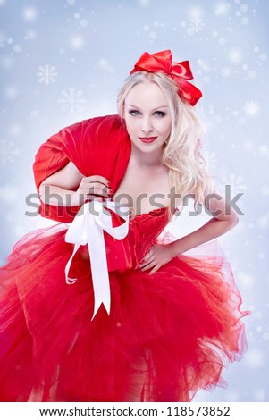 Beautiful young woman in Santa Claus clothes holding presents over Christmas background.