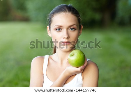 portrait pretty of woman with green apple . background summer park