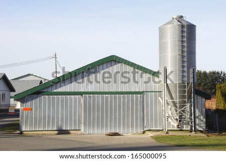 A modern, metal, prefabricated farm building with an adjoining silo/Prefabricated Farm Building/A modern, metal, prefabricated farm building with an adjoining silo