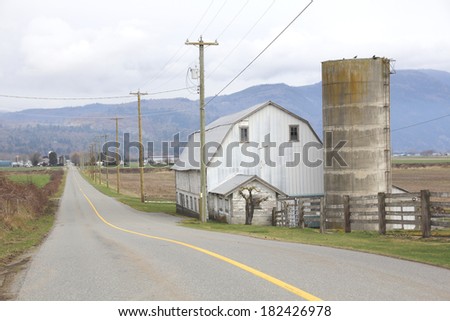 A barn and silo straddles a long, two lane rural road/Rural Road/A barn and silo straddles a long, two lane rural road