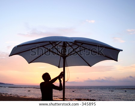 waiter takes down umbrella by the beach