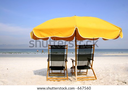 Yellow beach umbrella with deckchairs
