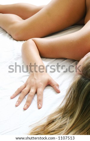 Nude woman lying on a white bed