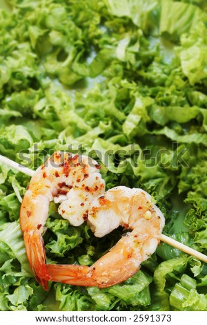 Two grilled prawns forming a heart shape on a green lettuce background