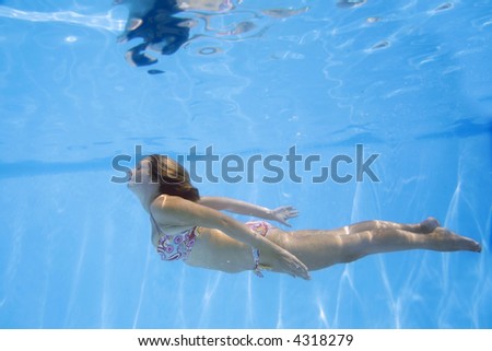 Pretty girl in bikini swimming underwater in blue pool