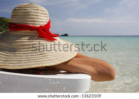 Pretty woman lying on the beach in a big sun hat
