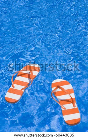 Pretty pair of stripey flip flops or thongs in a sparkling blue swimming pool