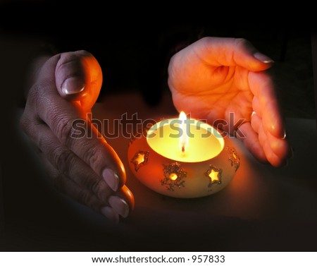 Woman's hands lit by a Christmas candle, dark background