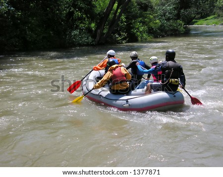 Five people in a rafting boat, rowing on the river